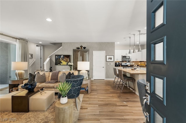 living room with light wood-style floors, recessed lighting, and stairway