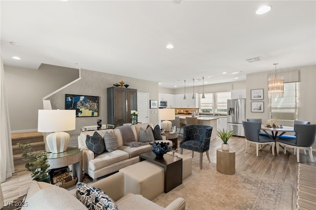 living room featuring visible vents, a notable chandelier, light wood-style flooring, and recessed lighting