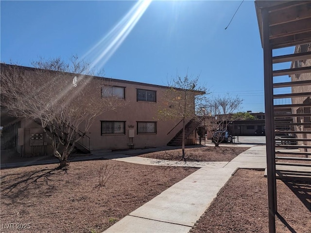 view of side of home with stairway and stucco siding