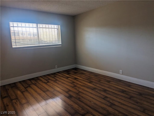 empty room featuring dark wood-style flooring, a textured ceiling, and baseboards