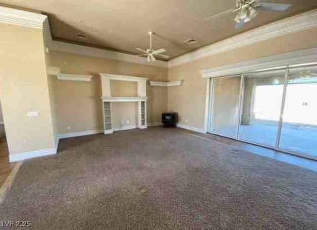 interior space with baseboards, a raised ceiling, a ceiling fan, crown molding, and dark carpet