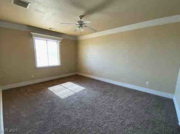 spare room with ornamental molding, dark colored carpet, visible vents, and baseboards