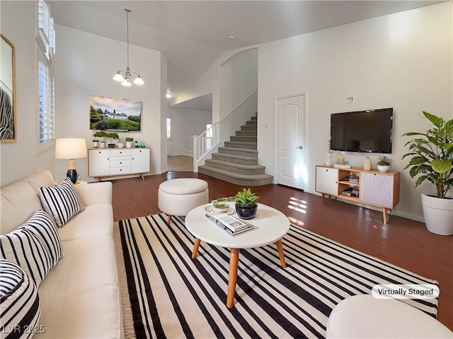 living area featuring stairs, high vaulted ceiling, an inviting chandelier, and wood finished floors