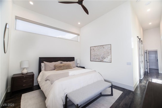 bedroom with a barn door, baseboards, dark wood finished floors, and recessed lighting