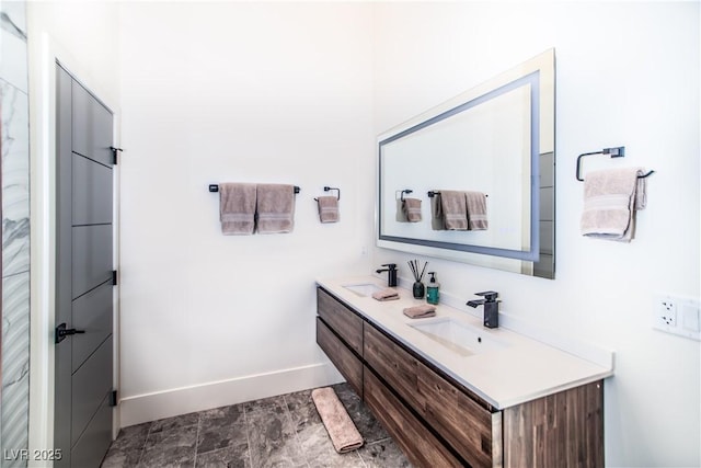 full bath with double vanity, baseboards, and a sink