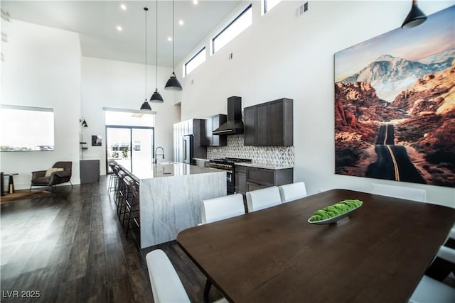 dining area featuring a high ceiling, dark wood-style flooring, visible vents, and recessed lighting