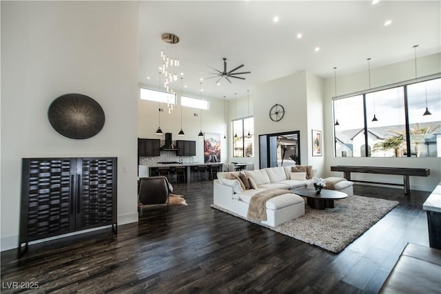 living room with recessed lighting, dark wood-style flooring, plenty of natural light, and a towering ceiling