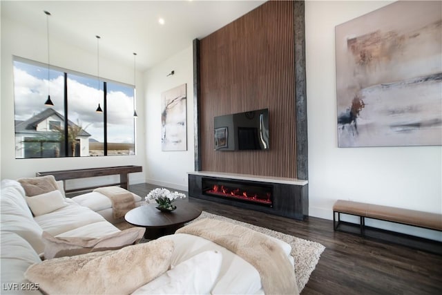 living area featuring dark wood-style floors, recessed lighting, baseboards, and a glass covered fireplace