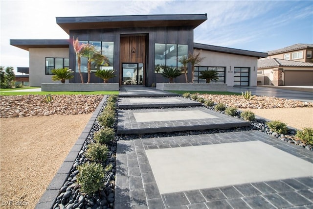 view of exterior entry featuring an attached garage, driveway, and stucco siding