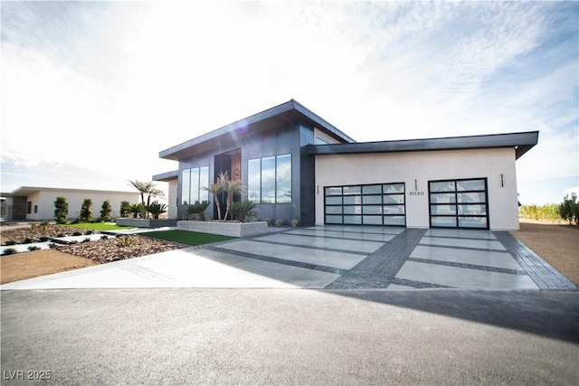 modern home featuring a garage, driveway, and stucco siding