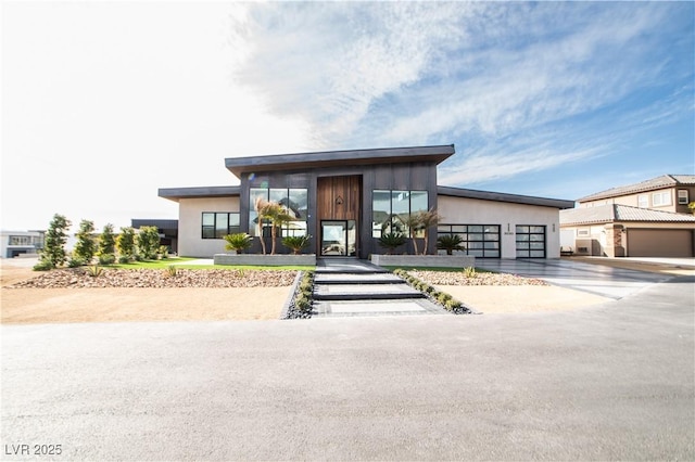 contemporary house featuring concrete driveway, an attached garage, and stucco siding