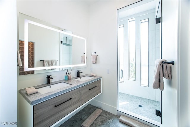 bathroom with a sink, a shower stall, baseboards, and double vanity