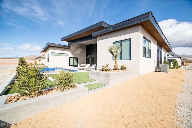 back of house featuring central AC unit, an outdoor pool, a patio, and stucco siding