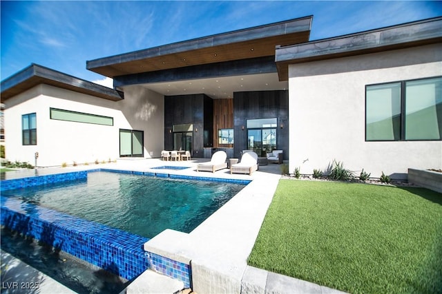 rear view of house featuring an outdoor pool, a patio area, a yard, and stucco siding