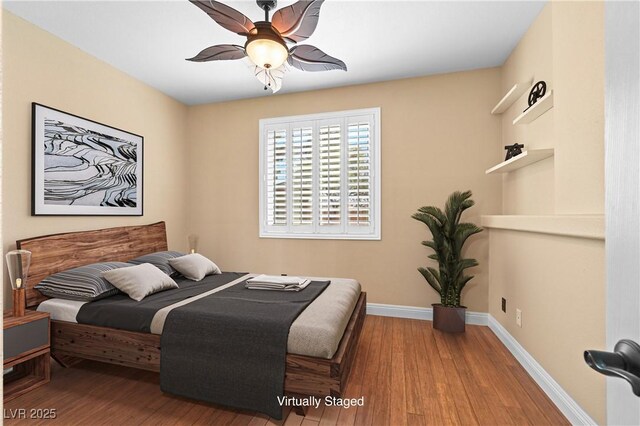 bedroom with a ceiling fan, wood finished floors, and baseboards