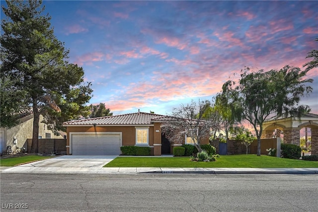 view of front of house featuring fence, stucco siding, a yard, a garage, and driveway