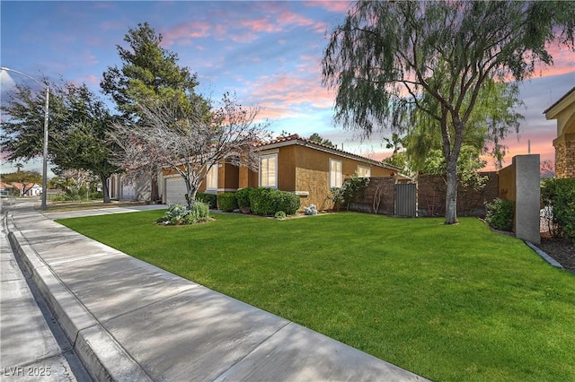 exterior space featuring fence, concrete driveway, stucco siding, a yard, and a garage