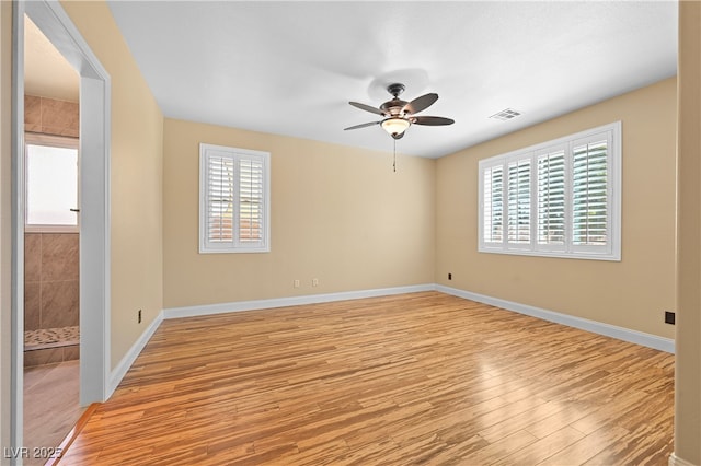 empty room featuring light wood finished floors, visible vents, ceiling fan, and baseboards