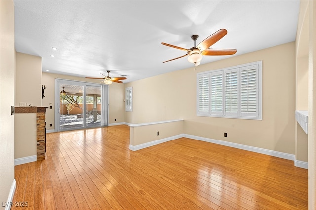 unfurnished living room with ceiling fan, baseboards, and light wood-style floors