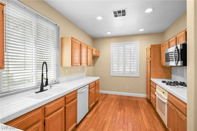 kitchen with visible vents, plenty of natural light, white appliances, and a sink