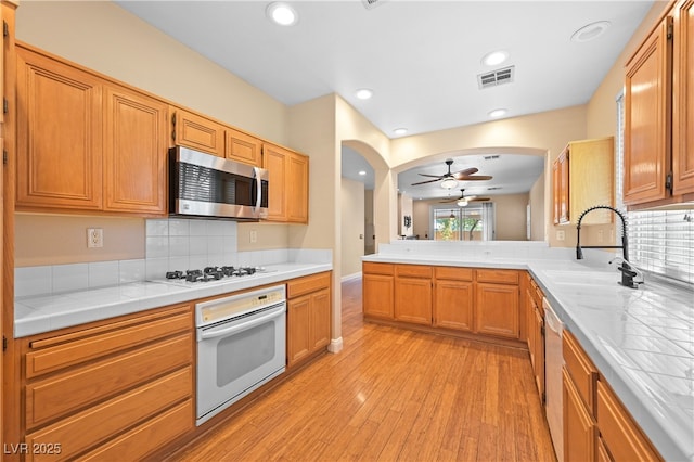 kitchen with visible vents, light wood-type flooring, arched walkways, stainless steel appliances, and a sink