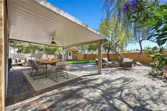 view of patio / terrace with outdoor dining area, an outbuilding, a fenced backyard, and outdoor lounge area