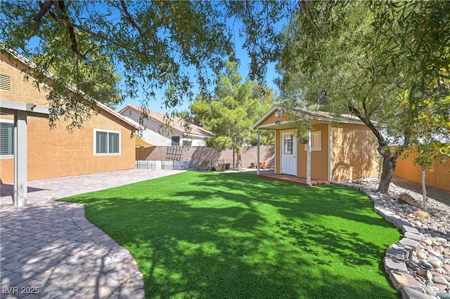 view of yard featuring a patio, an outbuilding, and a fenced backyard