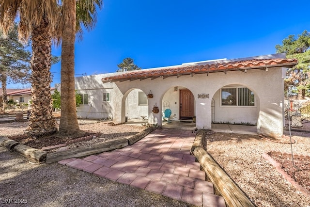 mediterranean / spanish home with a tiled roof and stucco siding