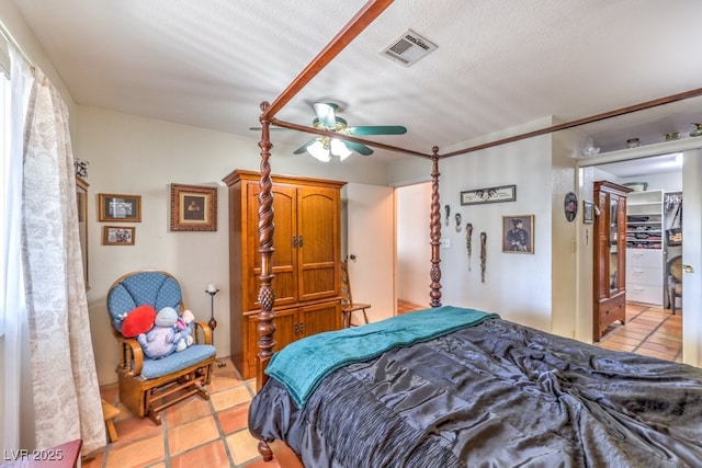 bedroom featuring a ceiling fan, visible vents, a textured ceiling, and light tile patterned floors