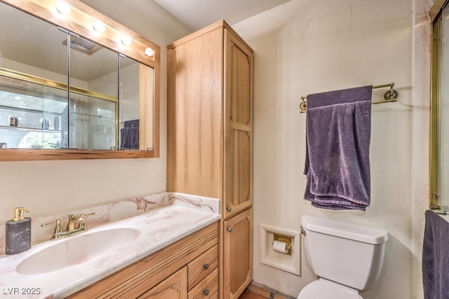 bathroom with toilet, vanity, and a shower with shower door