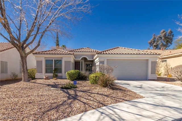 mediterranean / spanish home featuring concrete driveway, a tile roof, an attached garage, and stucco siding