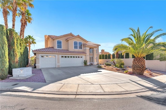 mediterranean / spanish-style home with a tile roof, stucco siding, an attached garage, fence, and driveway