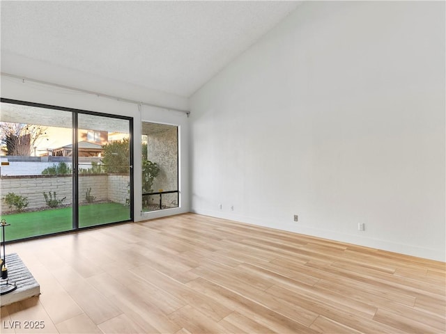 spare room featuring high vaulted ceiling, wood finished floors, and baseboards