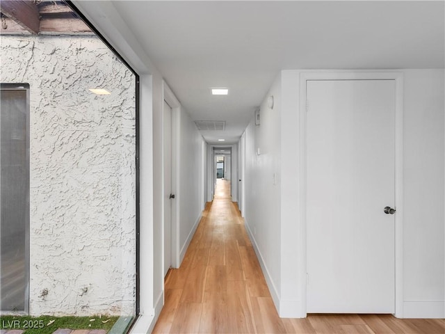 hall with light wood-style flooring and baseboards