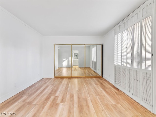 spare room featuring crown molding, wood finished floors, and baseboards