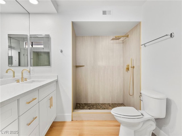 bathroom with toilet, wood finished floors, vanity, visible vents, and a shower