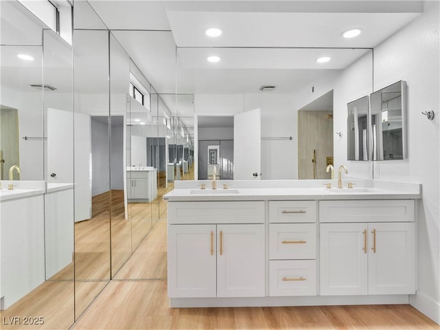 bathroom featuring double vanity, a sink, and recessed lighting