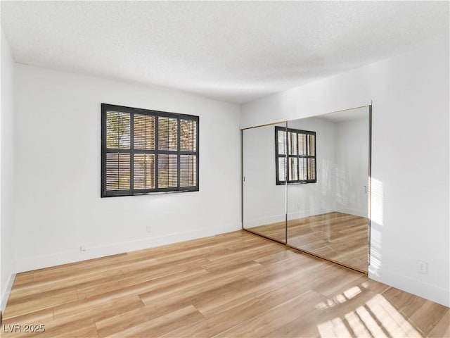 empty room featuring a textured ceiling, baseboards, and wood finished floors