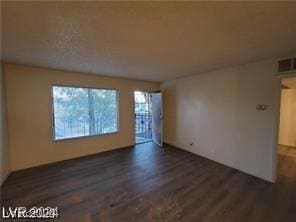 empty room featuring dark wood-style flooring and visible vents