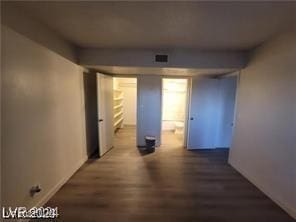 corridor featuring visible vents and dark wood-type flooring