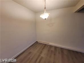 unfurnished dining area featuring dark wood-type flooring and baseboards