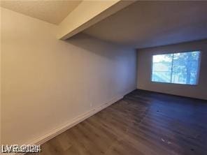 spare room with baseboards and dark wood finished floors