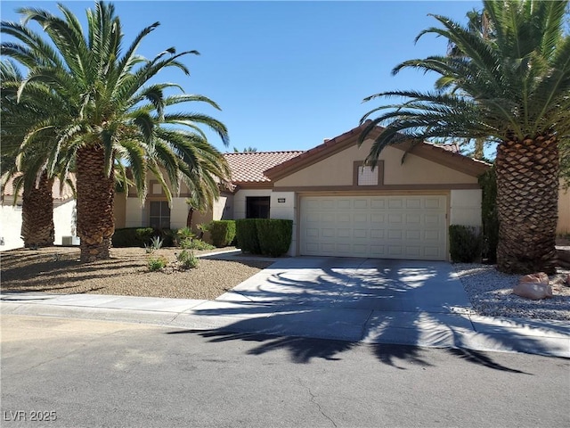 view of front of home featuring concrete driveway, a tile roof, an attached garage, and stucco siding