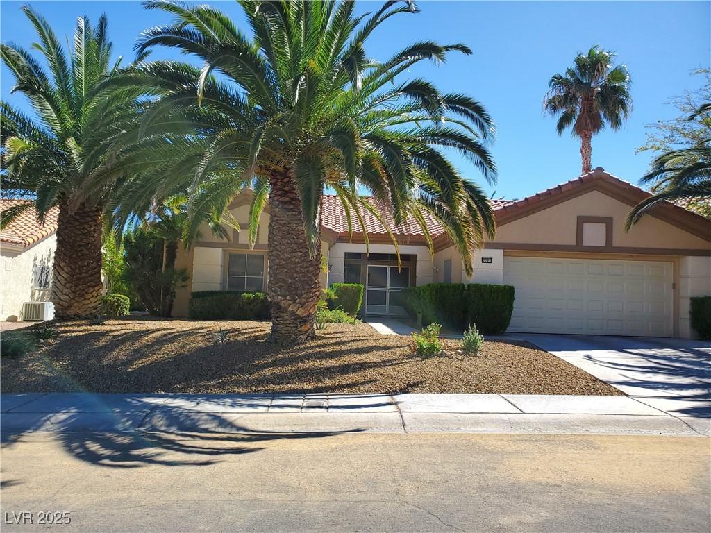 view of front of property with a garage, concrete driveway, a tile roof, and stucco siding