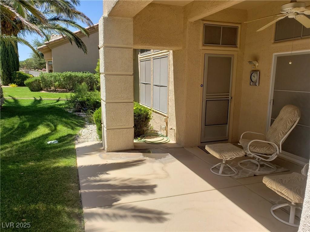 property entrance with a patio, a lawn, a ceiling fan, and stucco siding