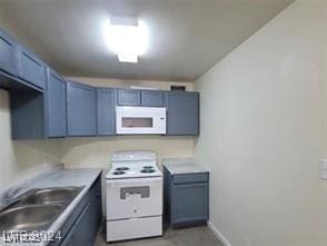 kitchen with white appliances, baseboards, blue cabinets, light countertops, and a sink