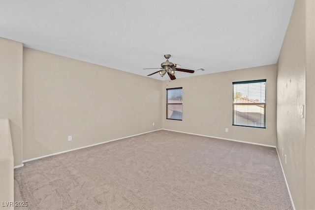 spare room featuring light carpet, ceiling fan, visible vents, and baseboards