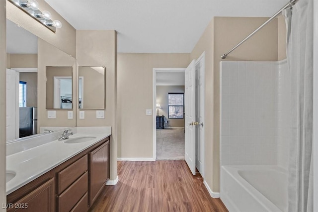 ensuite bathroom featuring double vanity, ensuite bath, shower / tub combo with curtain, wood finished floors, and a sink