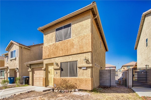 view of front facade featuring an attached garage, fence, driveway, a gate, and stucco siding