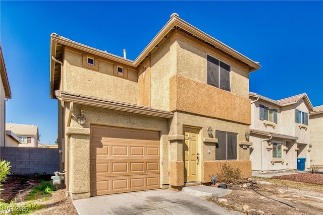 townhome / multi-family property with concrete driveway, fence, an attached garage, and stucco siding